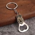 Detail of vintage wolf head embossed metal bottle opener keychain on a wooden surface - Wolf Head Design - Antique Bronze