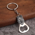 Detailed close-up of a vintage wolf head embossed metal keychain and bottle opener - Wolf Head Design - Antique Tin