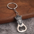 Close-up of vintage lion head bottle opener keychain with relief texture on wood surface - Lion Design - Antique Tin