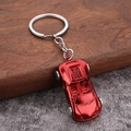 Polished bright red metal sports car keychain with silver flat ring on wooden surface - Red
