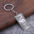 Detail view of a 100 dollar bill metal keychain with textured relief on wood surface - Oxidized White Gold Tone