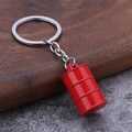 Vue détaillée d'un porte-clés bidon d'huile rouge miniature sur fond de bois sombre - Rouge
