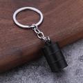 Gros plan d'un porte-clés baril d'huile 3D noir mat avec anneau en métal sur bois - Noir