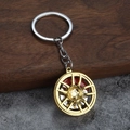 Detail eines goldenen Felgen Schlüsselanhängers mit roten Bremssätteln auf Holz Hintergrund - Gold