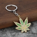 Vista macro del llavero hoja de arce chapado en oro con esmalte verde y cristales finos - Oro + Diamante de Imitación Blanco
