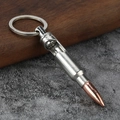 Detailed view of a bullet-shaped metal bottle opener keychain on a rustic wooden surface - White K/Silver