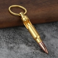 Macro detail of bullet shaped bottle opener keychain on a wooden and stone surface - Gold