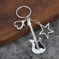 Detailed close-up of guitar keychain with black and white enamel finish and silver star - Large Hollow / White