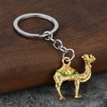 Macro shot of golden camel keychain with intricate enamel detailing and metallic ring - Gold + Green Enamel