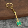 Dettaglio portachiavi a liuto Pipa dorato con smalto verde su fondo pietra e legno - Verde