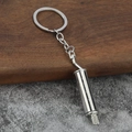 Polished silver car exhaust muffler keychain made of metal on industrial wooden desk - Silver