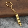 Detailed close-up of a glossy gold exhaust pipe keychain on a textured surface - Gold