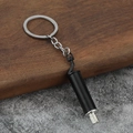 Macro detail of matte black car exhaust pipe keychain with metallic silver accents - Black