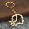 Close-up of golden elephant keychain with white enamel inlay and pink dot details - Gold Base White