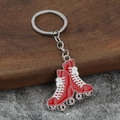 Close-up of red roller skate keychains with silver finish on a wooden stand - Red