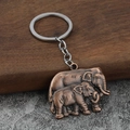 Dettaglio portachiavi in lega di bronzo con elefante madre e figlio su fondo in legno - Rosso Antico