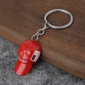 Portachiavi cappello MAGA rosso con anello in metallo su superficie in legno e pietra - Rosso