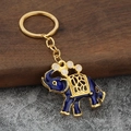 Vista macro del portachiavi a forma di elefante in smalto blu con dettagli dorati e bianchi - Blu