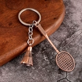Detalle macro de un llavero de bádminton de bronce vintage con raqueta y volante de metal - Rojo Antiguo