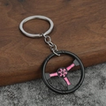Dettaglio di un portachiavi a forma di volante da corsa con ruota nera e dettagli rosa - Rosa
