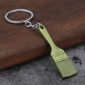 Creative green paint brush keychain made of textured alloy metal on a stone surface - Bronze