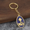 Golden keychain with oval blue pendant featuring embossed religious chalice and vine symbols - Imitation Gold / Blue Background