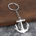 Silver nautical anchor keychain with decorative chain on a rustic wooden surface - Silver