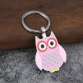 Roze emaille uil metalen sleutelhanger met zilveren ring op houten en stenen ondergrond - Roze