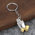 Two-tone praying hands keychain in silver and gold alloy finish on a rustic stone background - Silver Palm Gold Cuff (White K)