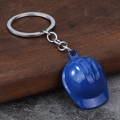 Detailed close-up of a blue mini safety helmet keychain on a dark wooden background - Blue