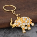 Detailed macro view of the golden elephant keychain with colorful enamel dots on wood - Orange