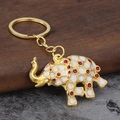 Detailed view of elephant keychain with white enamel petals and red gemstone accents - Red