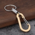 Close-up of golden D-ring carabiner and silver spring loop on a wooden surface - Gold Square Style