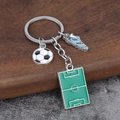 Detail of soccer themed keychain featuring mini ball, cleat and green pitch charms - Football