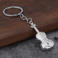 Dettaglio ravvicinato di un portachiavi a forma di violino in metallo argento su legno - Argento