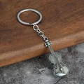Macro detail of a vintage silver violin keychain on a rustic wooden and stone surface - Antique Pewter