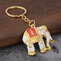 Exquisiter thailändischer Elefanten-Schlüsselanhänger in Gold mit roter Emaille und Details - Weiß