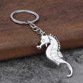 Portachiavi a forma di cavalluccio marino in metallo lucido su sfondo rustico in legno - Argento