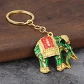 Exquisiter goldener Elefant Schlüsselanhänger mit grünem Emaille auf rustikalem Holzhintergrund - Grün