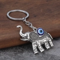 Detailed close-up of a vintage silver elephant keychain with blue evil eye bead and engraving - Elephant