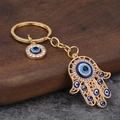 Detail of Hamsa Hand and Evil Eye gold keychain with blue crystals on stone - Large Hamsa Hand