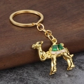 Exquisite golden camel keychain with green gemstone details and polished metal surface - Gold Green