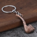 Vintage Pfeife Schlüsselanhänger aus Bronze auf Holz und Stein Hintergrund Dekor - Antik Rot