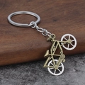 Detailed macro of a vintage dual-tone alloy bicycle keychain on a textured surface - Bronze