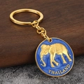 Llavero de elefante dorado con colgante de esmalte azul de Tailandia sobre madera - Azul