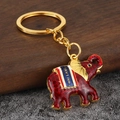 Golden elephant keychain with red enamel and blue Thailand banner on wooden base - Red