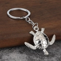 Silver turtle keychain featuring a detailed textured shell on a rustic wooden surface - Silver (White K)