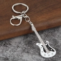 Vue détaillée du porte-clés guitare électrique avec strass et finition en émail - Argent + Blanc & Noir