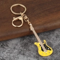 Détail d'un porte-clés guitare électrique avec émail jaune et strass brillants sur métal doré - Or KC + Jaune