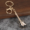 Dettaglio di portachiavi a chitarra in lega dorata con strass lucidi e inserti in smalto - Oro KC + Nero